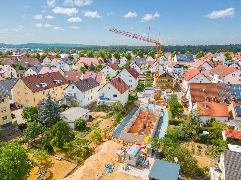 Luftbild einer Baustelle mit Kran inmitten von Wohnhäusern