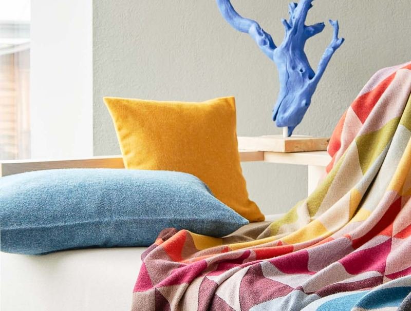 Gelbes und blaues Kissen neben der Wohndecke auf dem Sofa