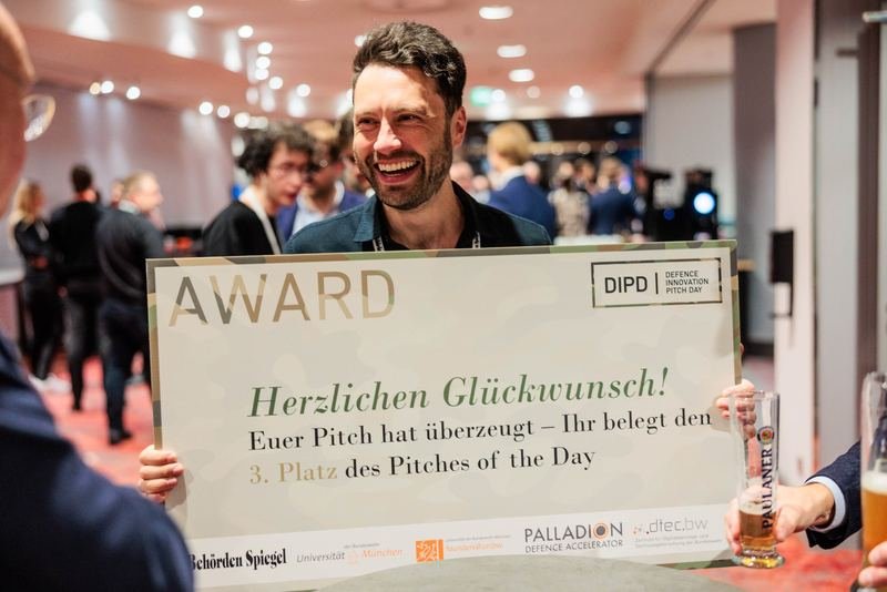 Preisträger hält ein Award-Schild bei einer Pitch-Veranstaltung