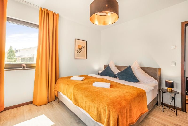 Hotelzimmer mit orangefarbener Tagesdecke und Vorhängen