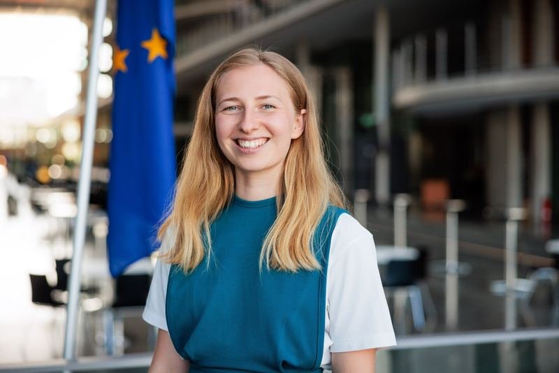 Businessporträt einer jungen Frau vor einer Europaflagge
